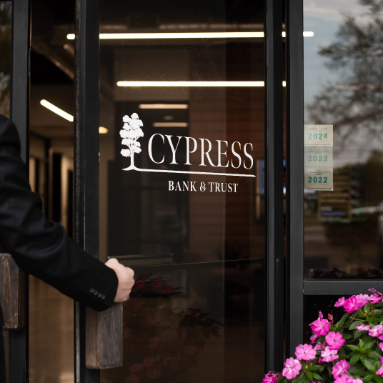 Persona abriendo la puerta de Cypress Bank & Trust