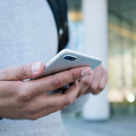 Persona usando teléfono inteligente al aire libre, vista en primer plano.