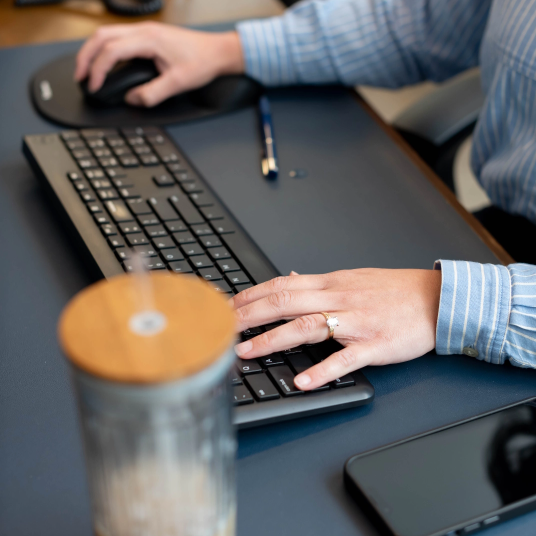 Persona escribiendo en el teclado, sosteniendo el ratón