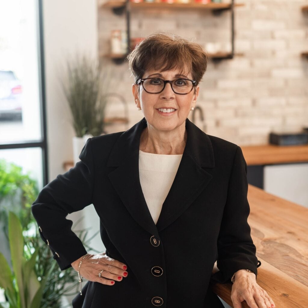 Smiling woman in black suit, standing in office