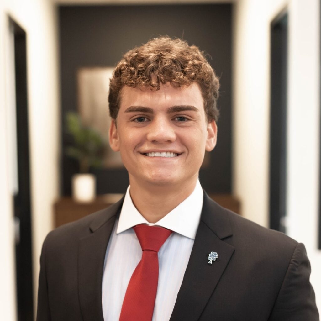 Smiling young man in a suit and red tie.