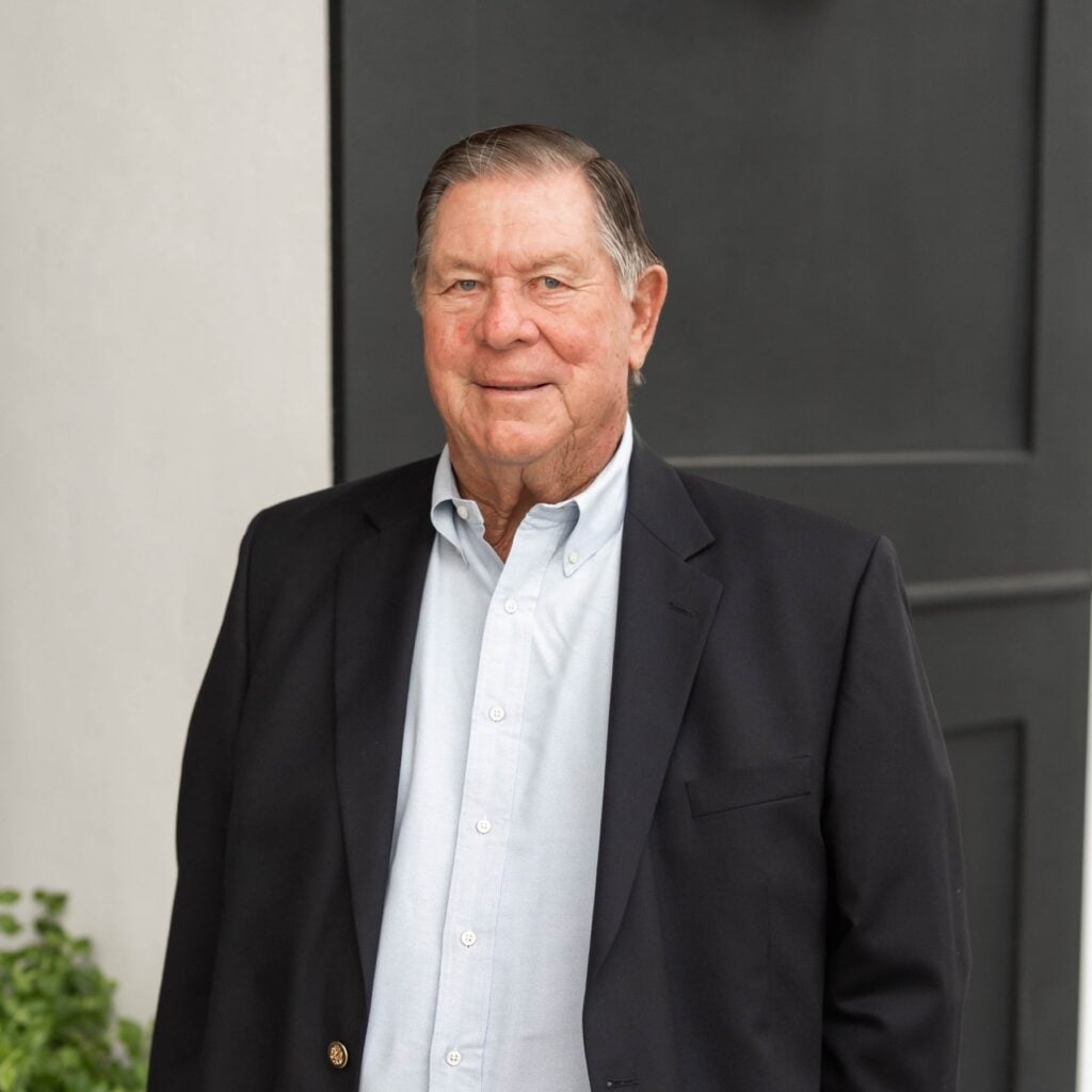 Smiling man in suit standing outside a building.