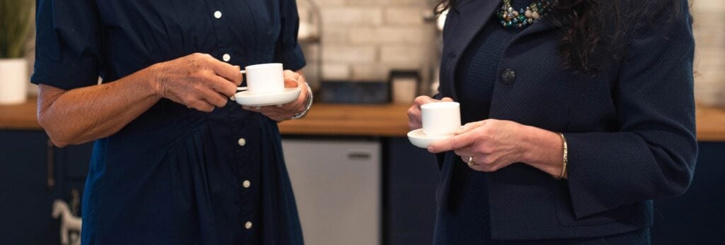 Two women holding coffee cups chatting
