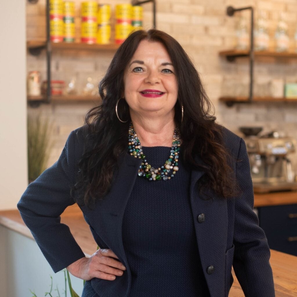 Smiling woman in business attire at a cafe.