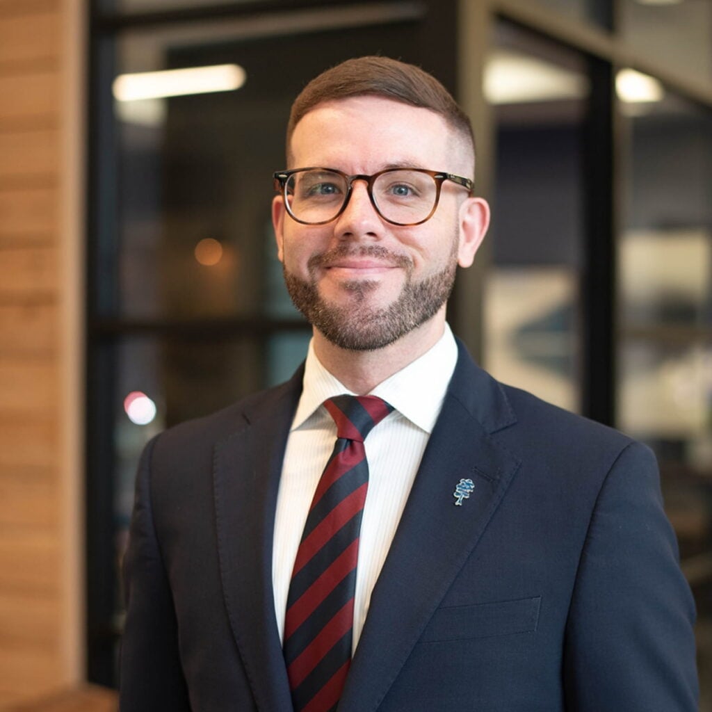 Smiling man in glasses wearing a suit and striped tie