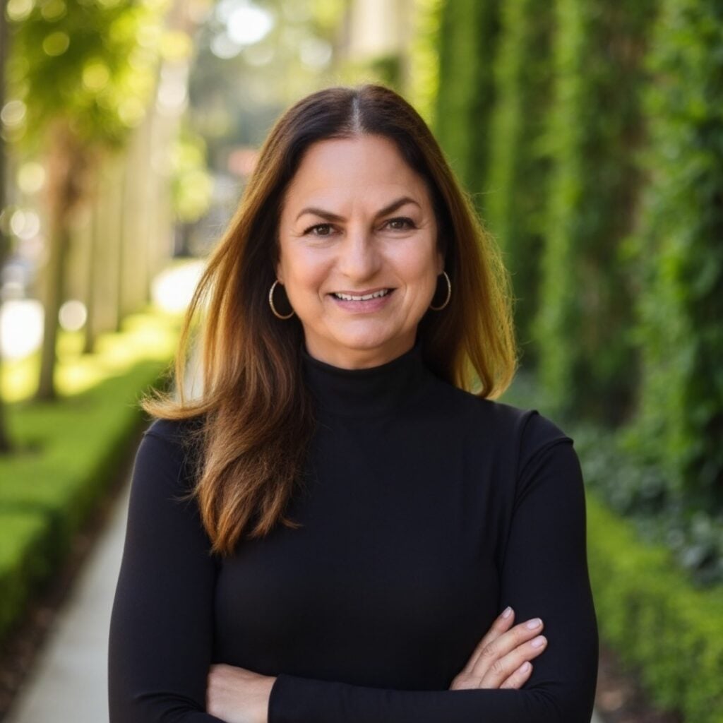 Smiling woman outdoors with green hedge background