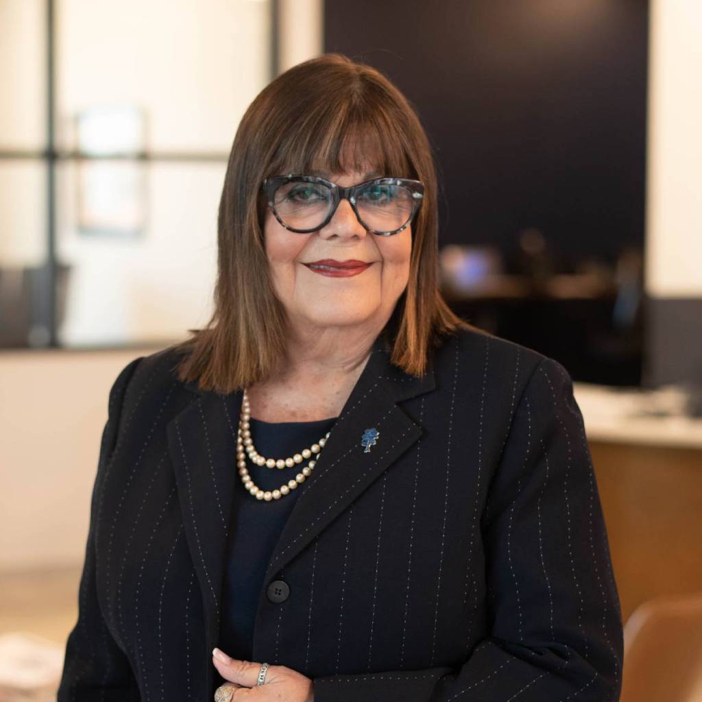 Smiling woman wearing glasses and a suit indoors