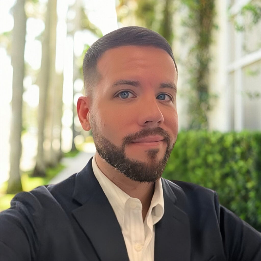 Man in suit smiling outdoors near palm trees