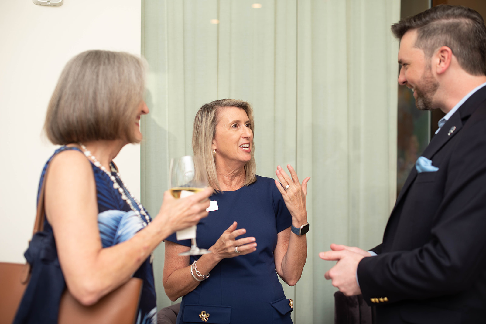 Tres invitados conversan en un evento social en interiores