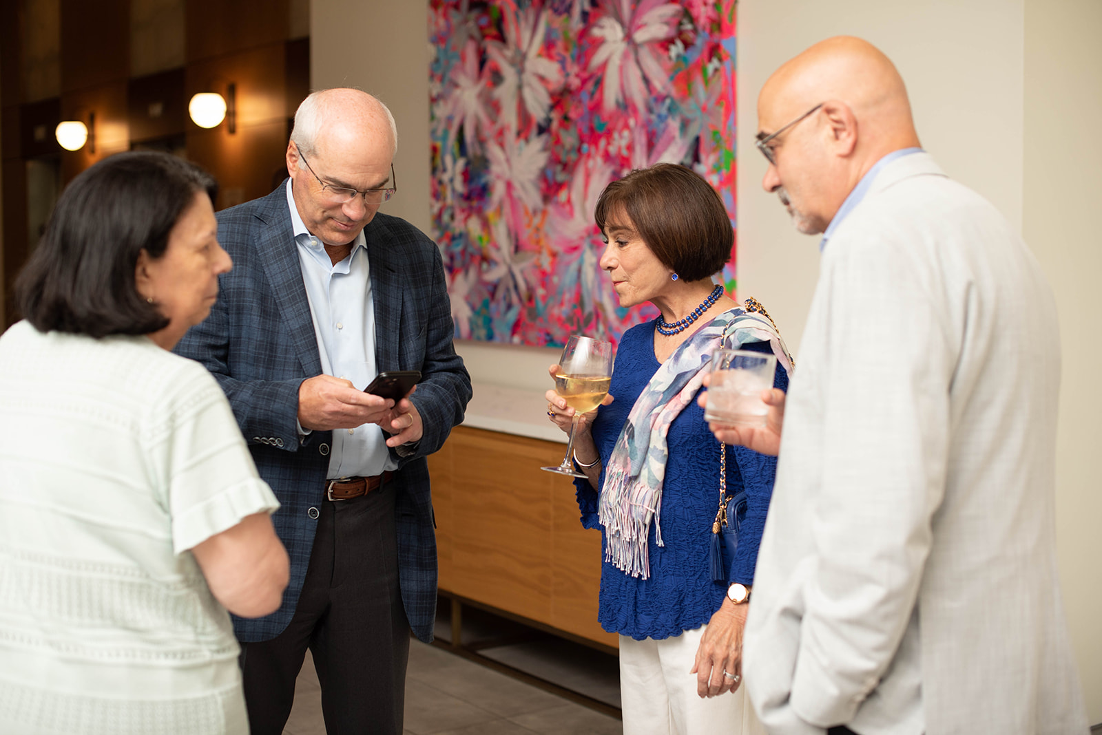 Cuatro invitados socializan en una recepción en una galería de arte.