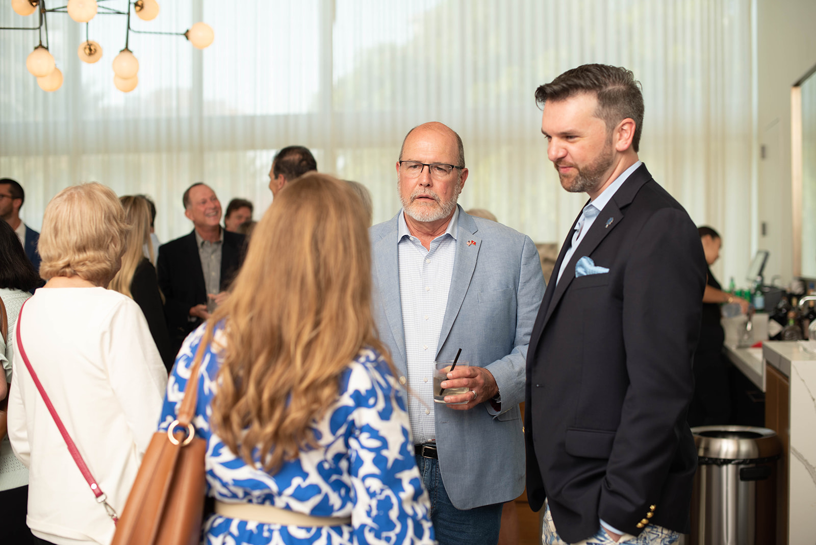 Los invitados conversan en un brillante evento de networking en interiores.