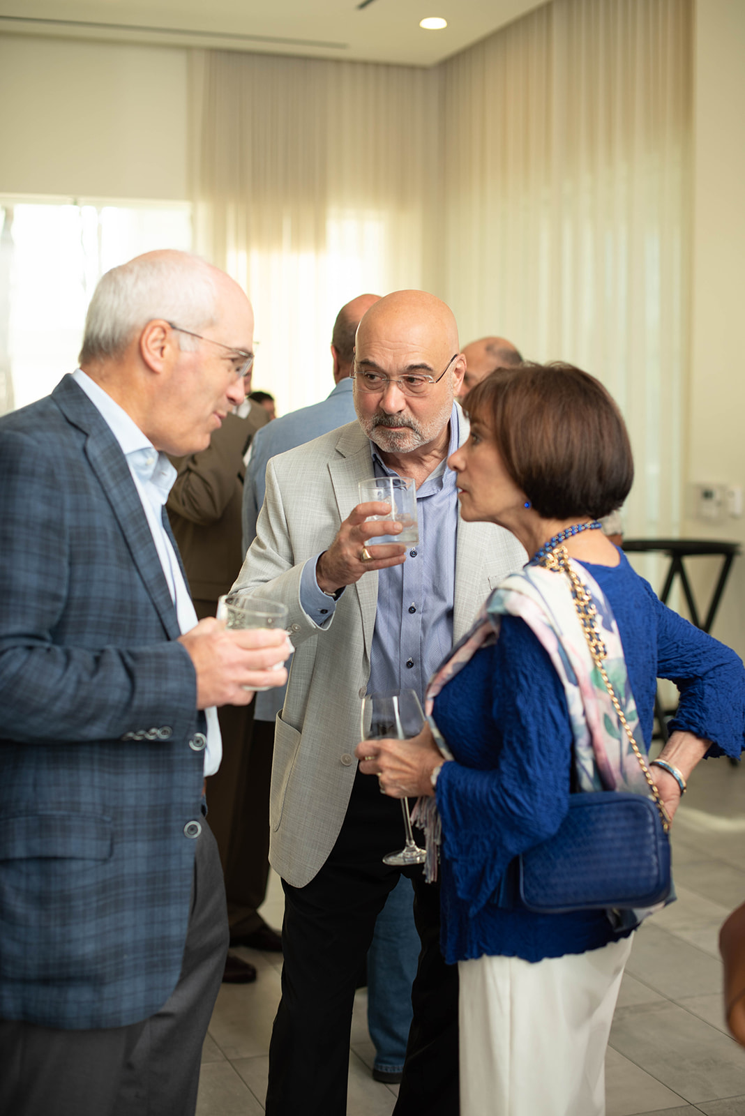 Tres invitados conversan mientras sostienen bebidas en la recepción