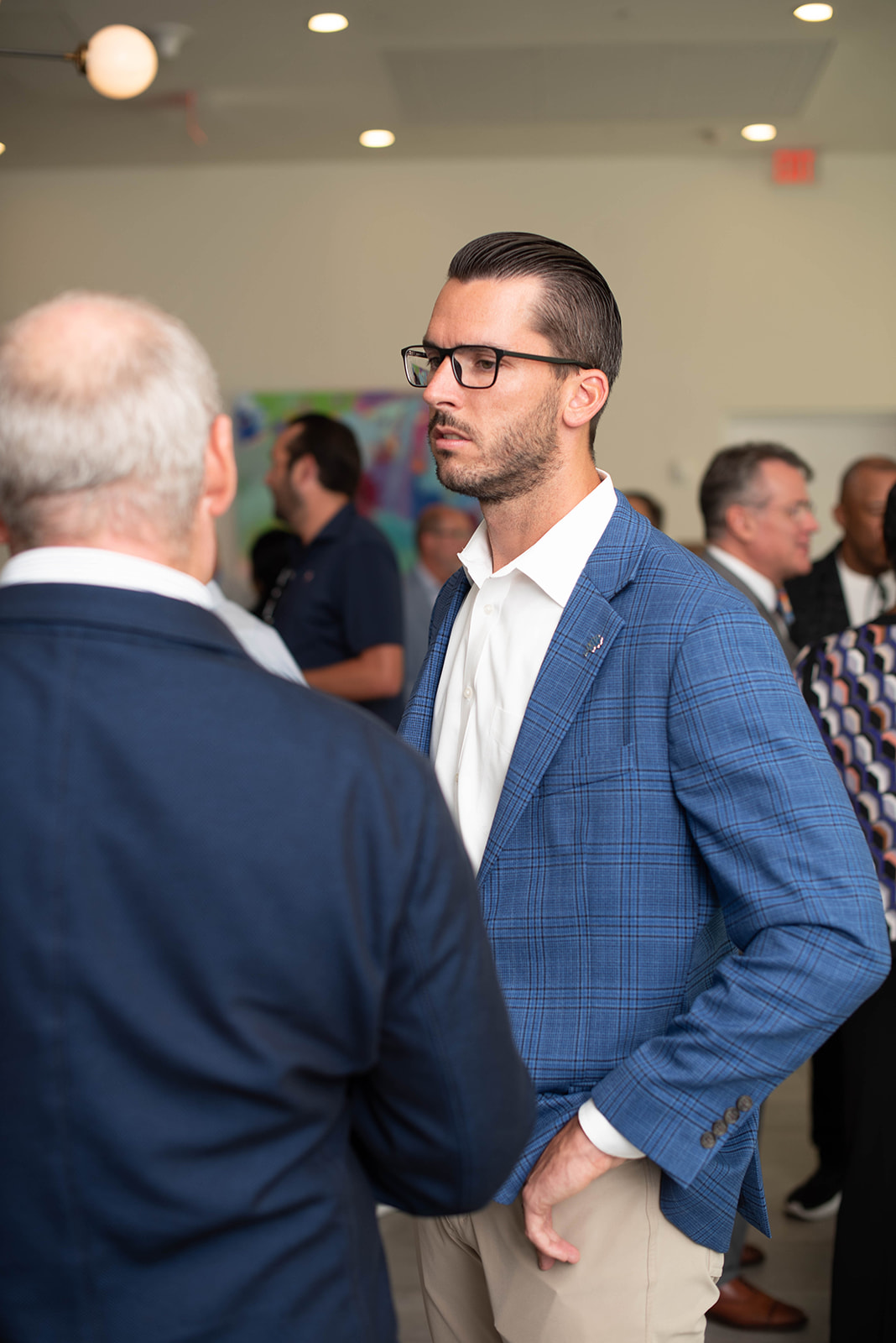 Hombre con blazer azul de cuadros haciendo networking en un evento en interiores