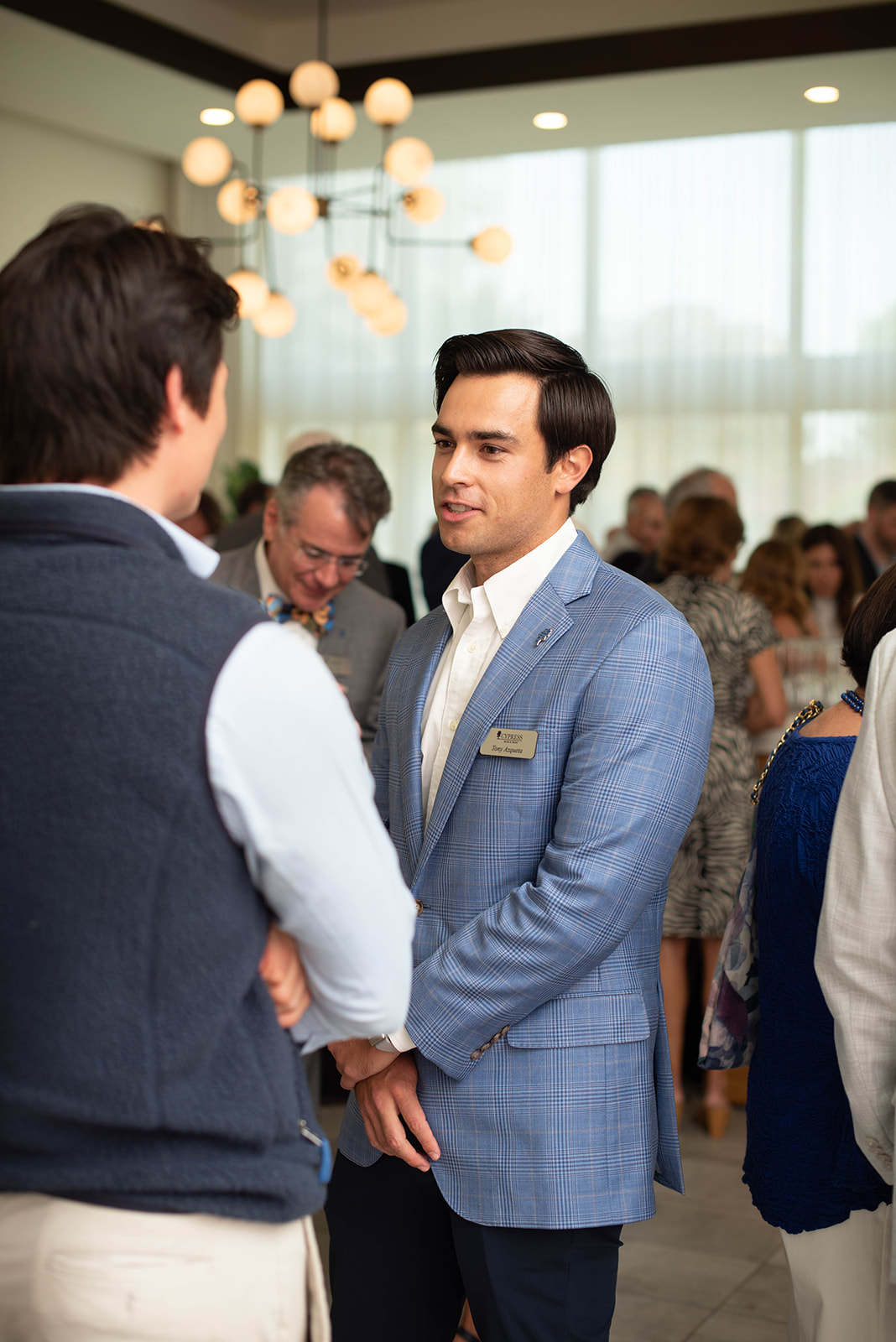 Dos hombres conversan en un evento de networking en interiores y concurrido.