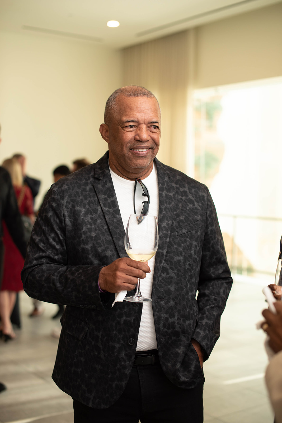 Hombre sonriendo sosteniendo una copa de vino en un evento en interiores