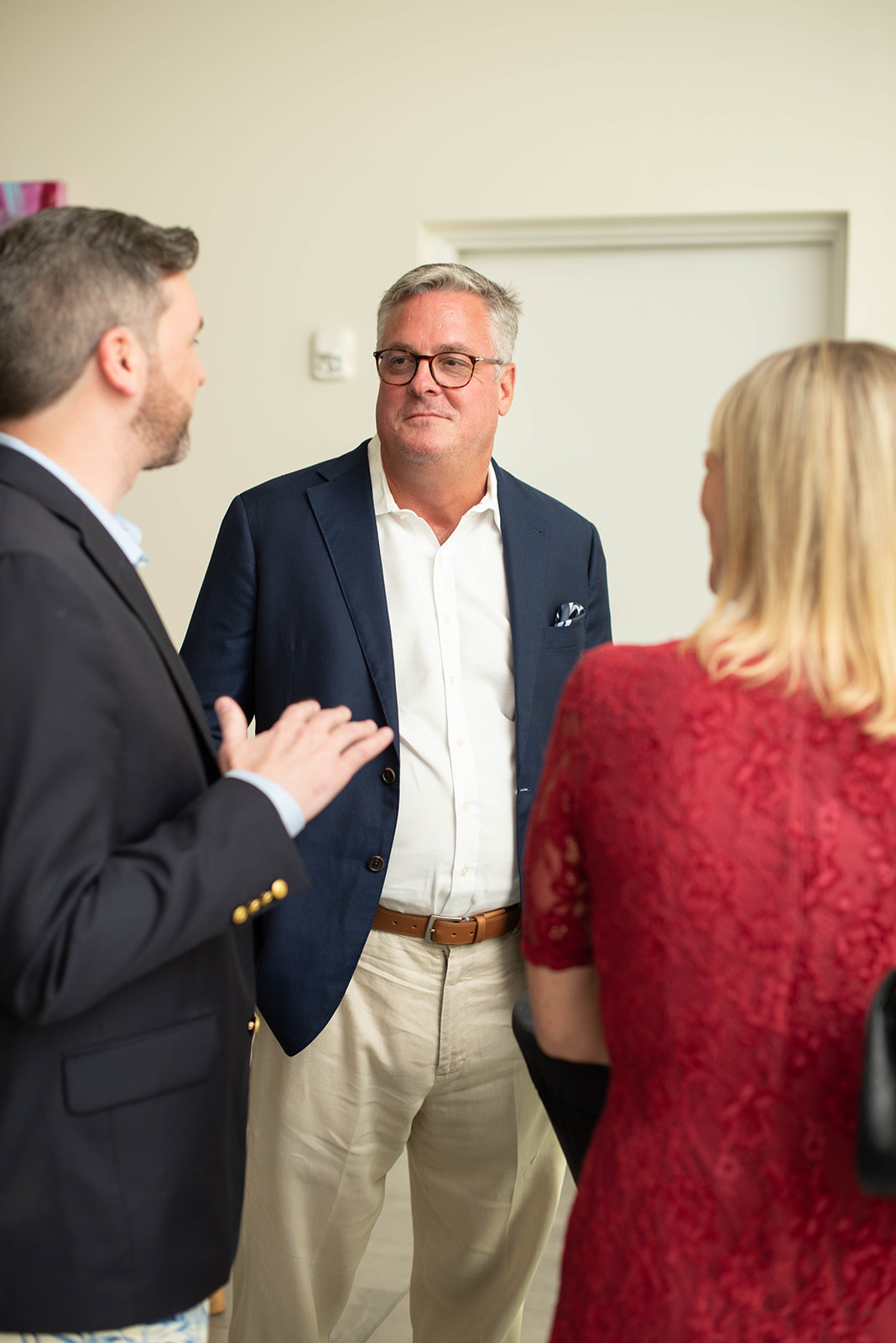 Tres profesionales conversan en un evento de networking en interiores.