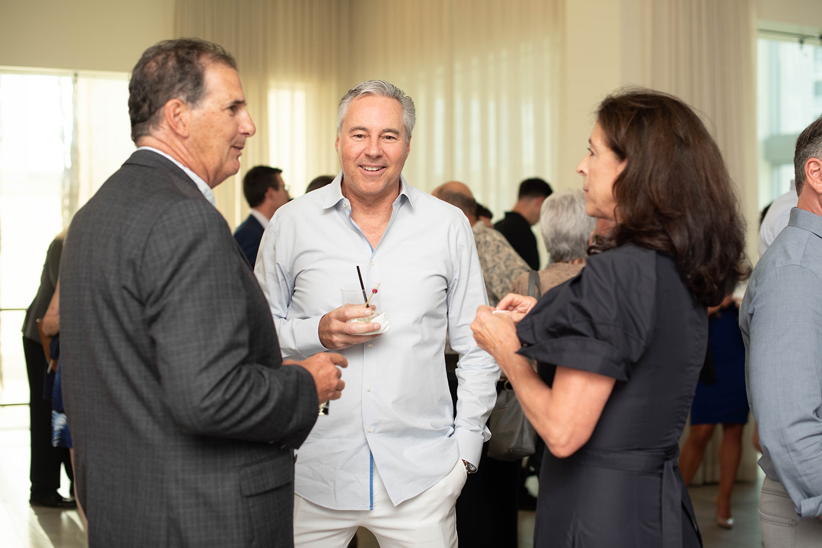 Los invitados conversan en una recepción de networking interior y luminosa.