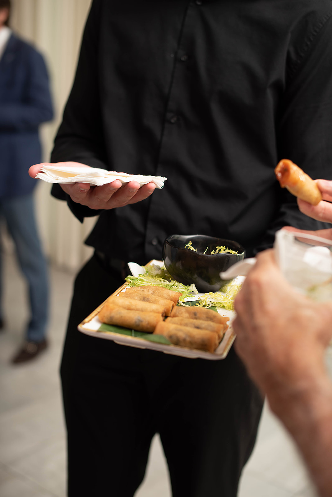 El servidor ofrece rollitos de primavera fritos en una bandeja.