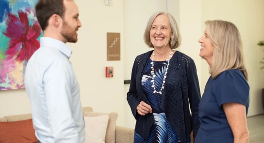 Tres adultos charlando en la recepción de una oficina moderna