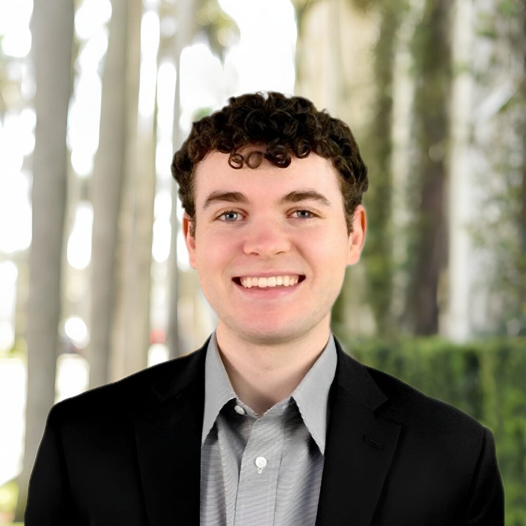 Smiling young man in blazer against blurred outdoor background
