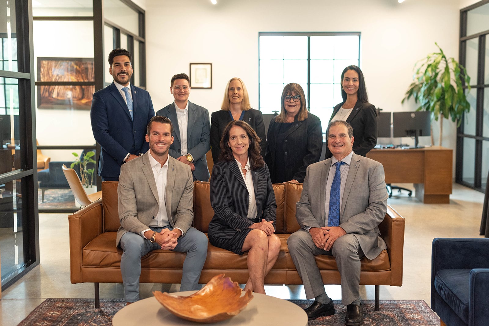 Ocho profesionales de negocios posan en una oficina moderna.