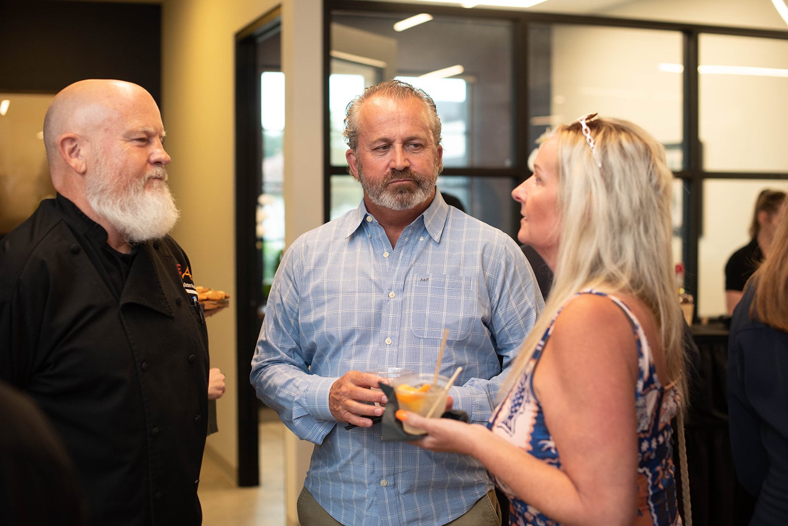 Tres invitados conversan en un evento social en interiores