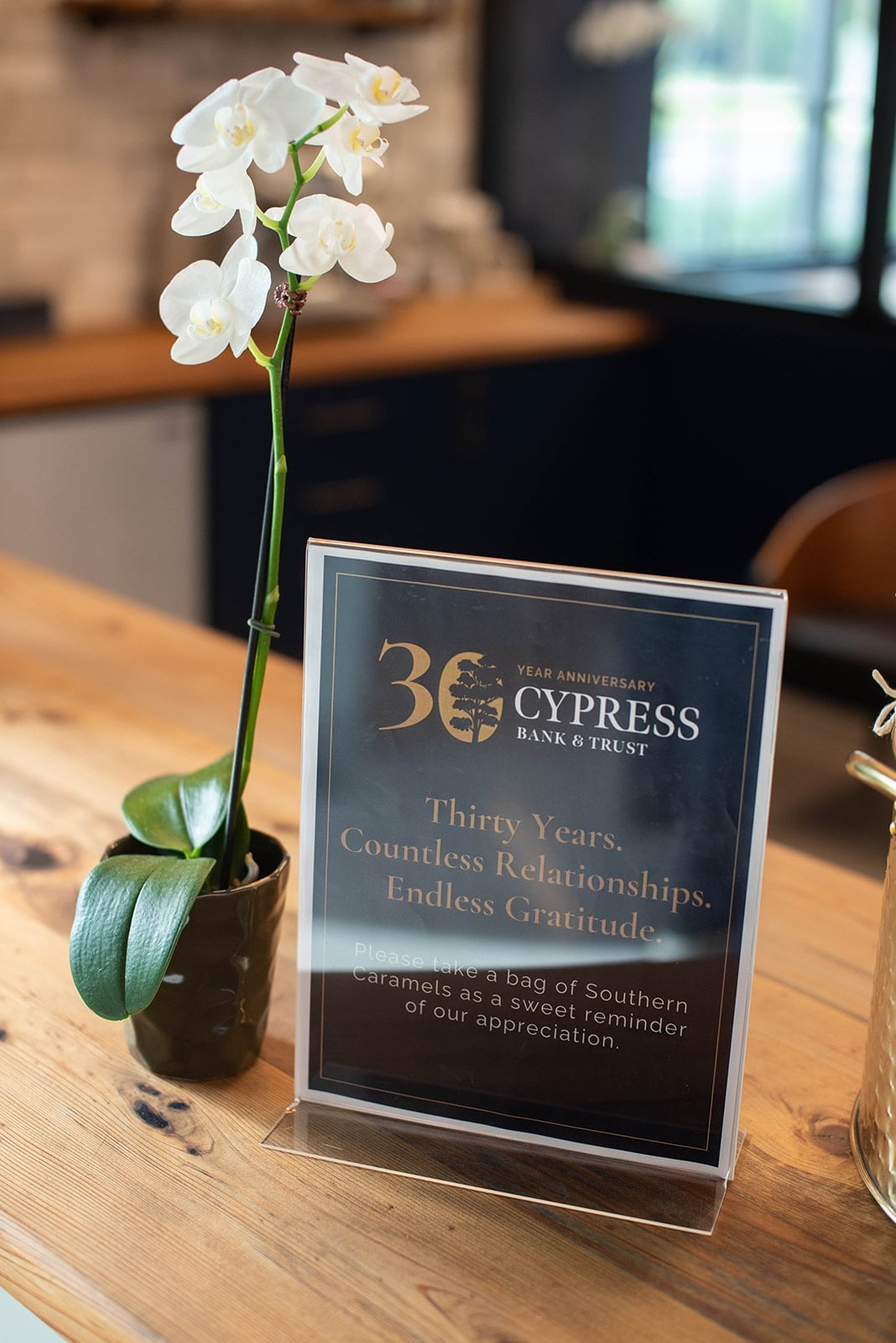 Orquídea blanca junto a la señal del 30 aniversario de Cypress Bank