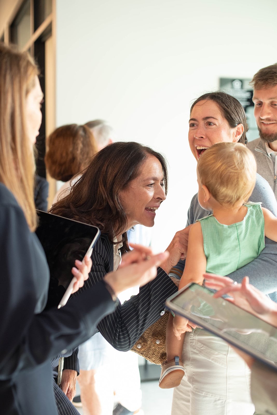 Adultos sonriendo saludan a un niño pequeño en una reunión
