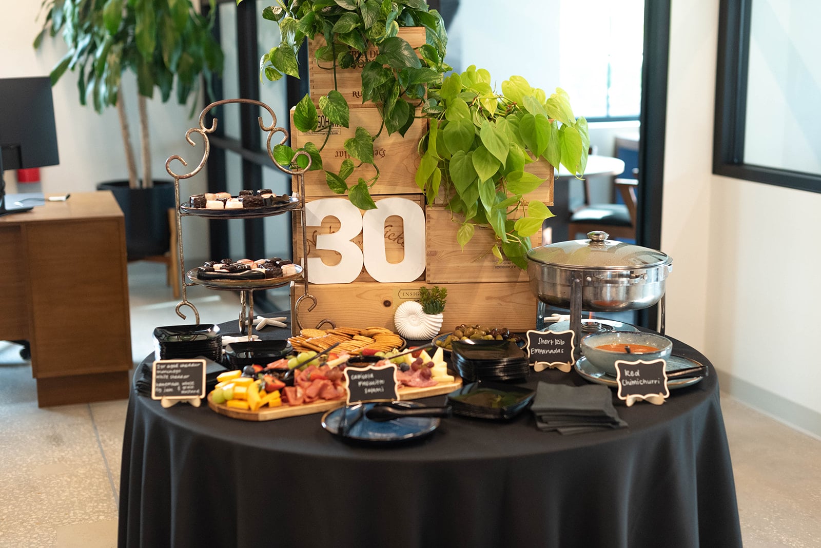 Mesa de aperitivos temáticos de treinta con plantas verdes exuberantes