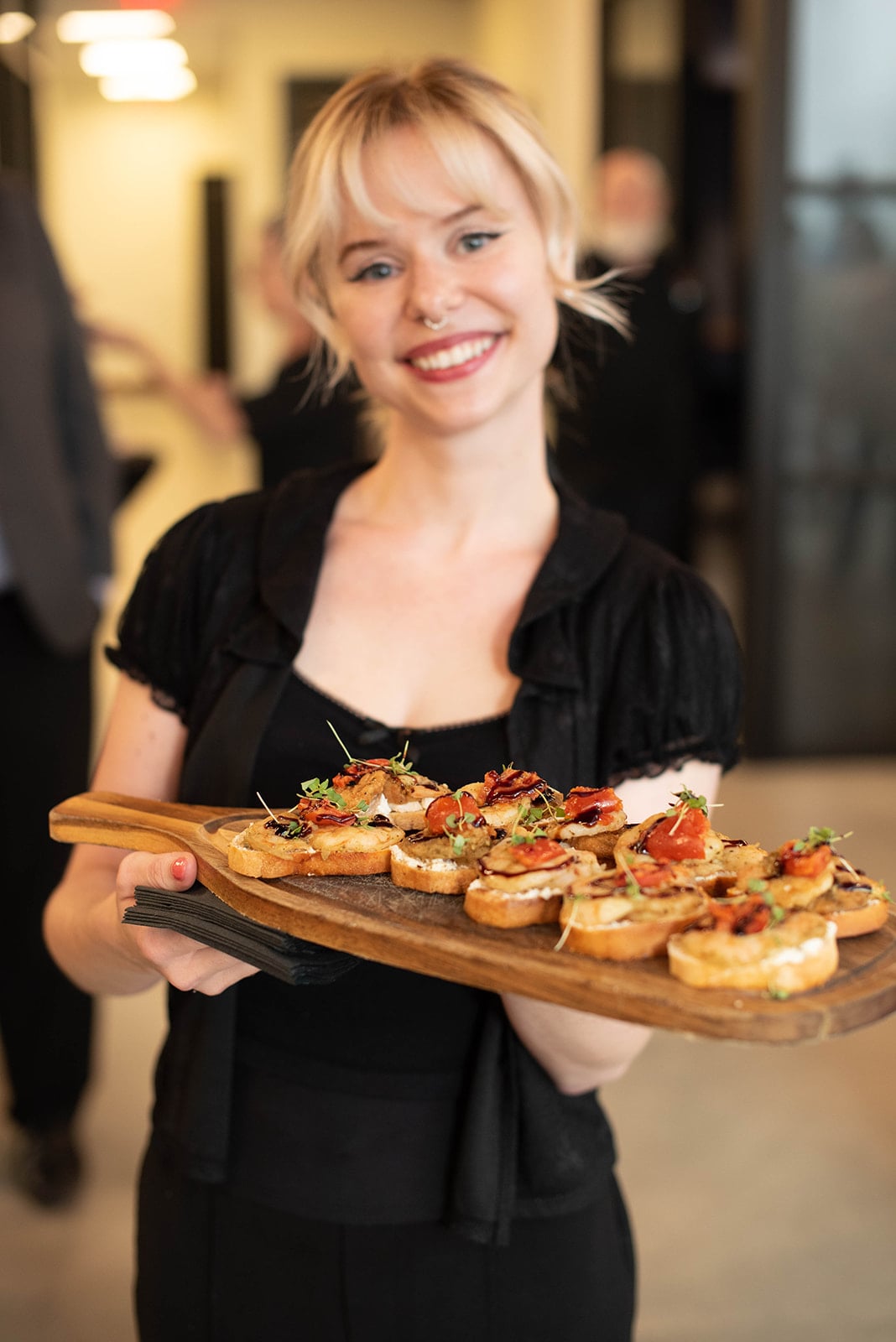 Servidor sonriendo sosteniendo una bandeja de aperitivos de bruschetta