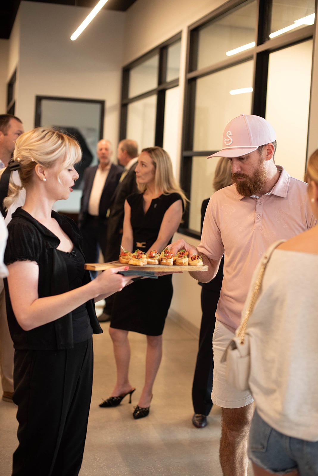 El invitado selecciona un aperitivo de la bandeja del camarero en un evento en interiores