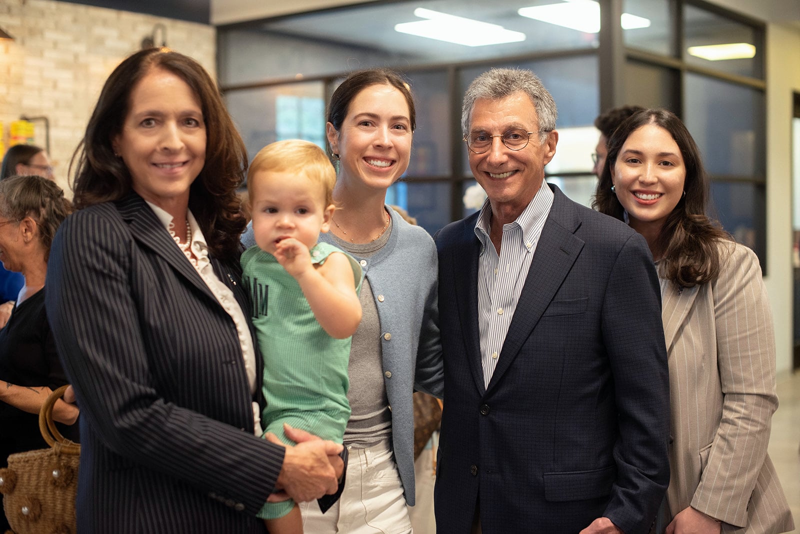 Cuatro adultos y un bebé sonriendo en una reunión en interiores
