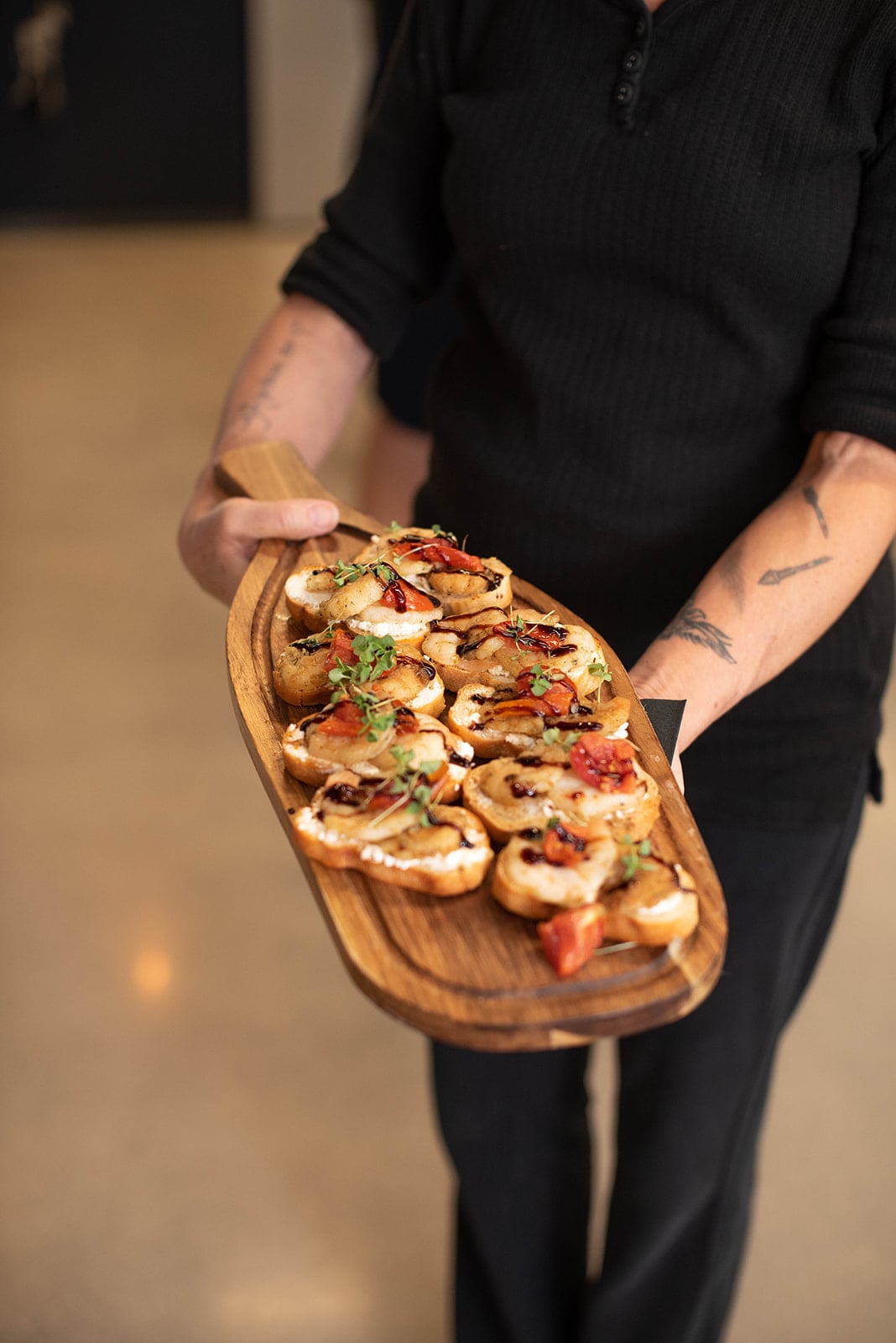 El servidor sostiene una tabla de madera con aperitivos de bruschetta gourmet
