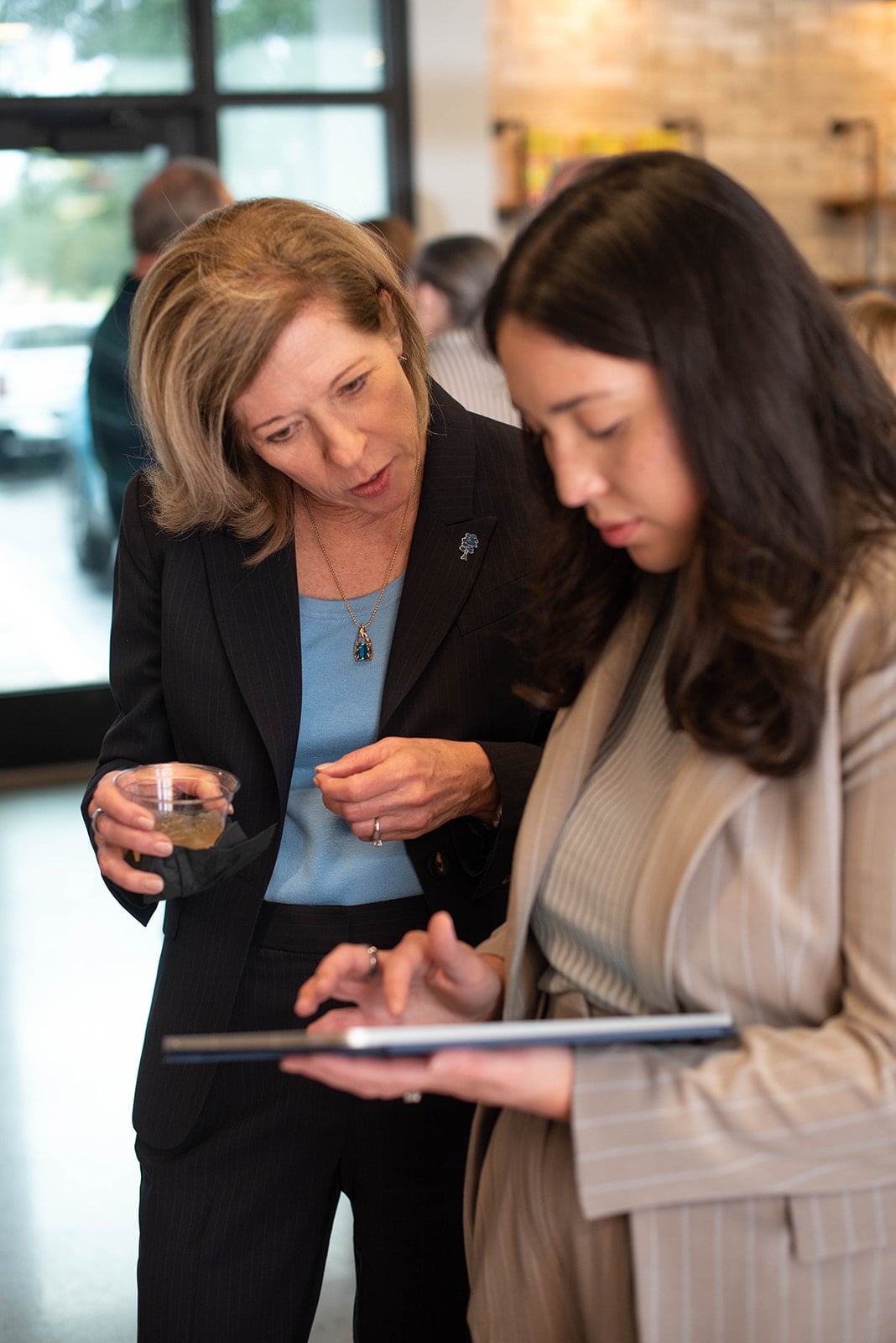 Dos mujeres revisan una tableta en un evento de networking.