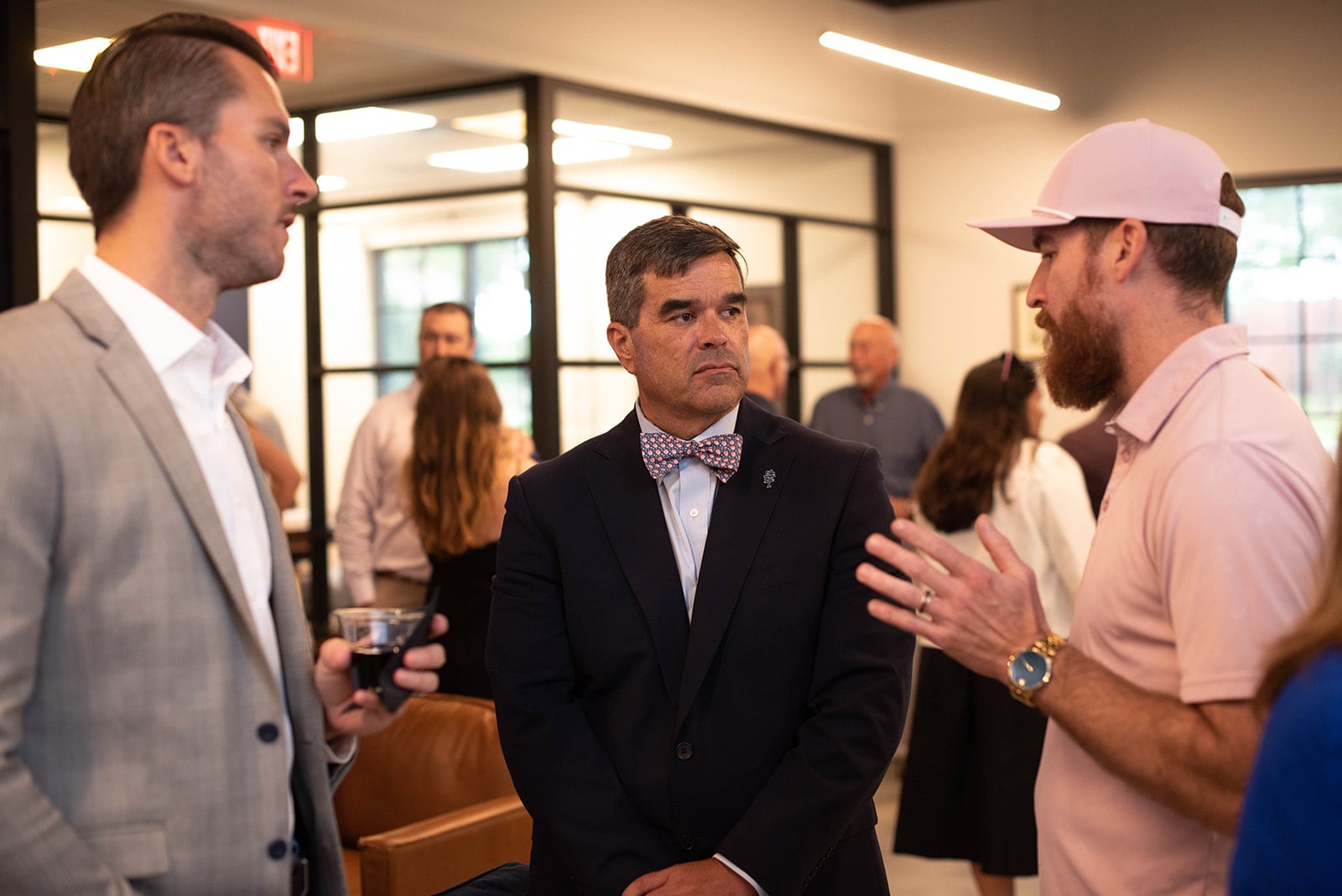 Tres hombres conversan en un evento de networking en interiores