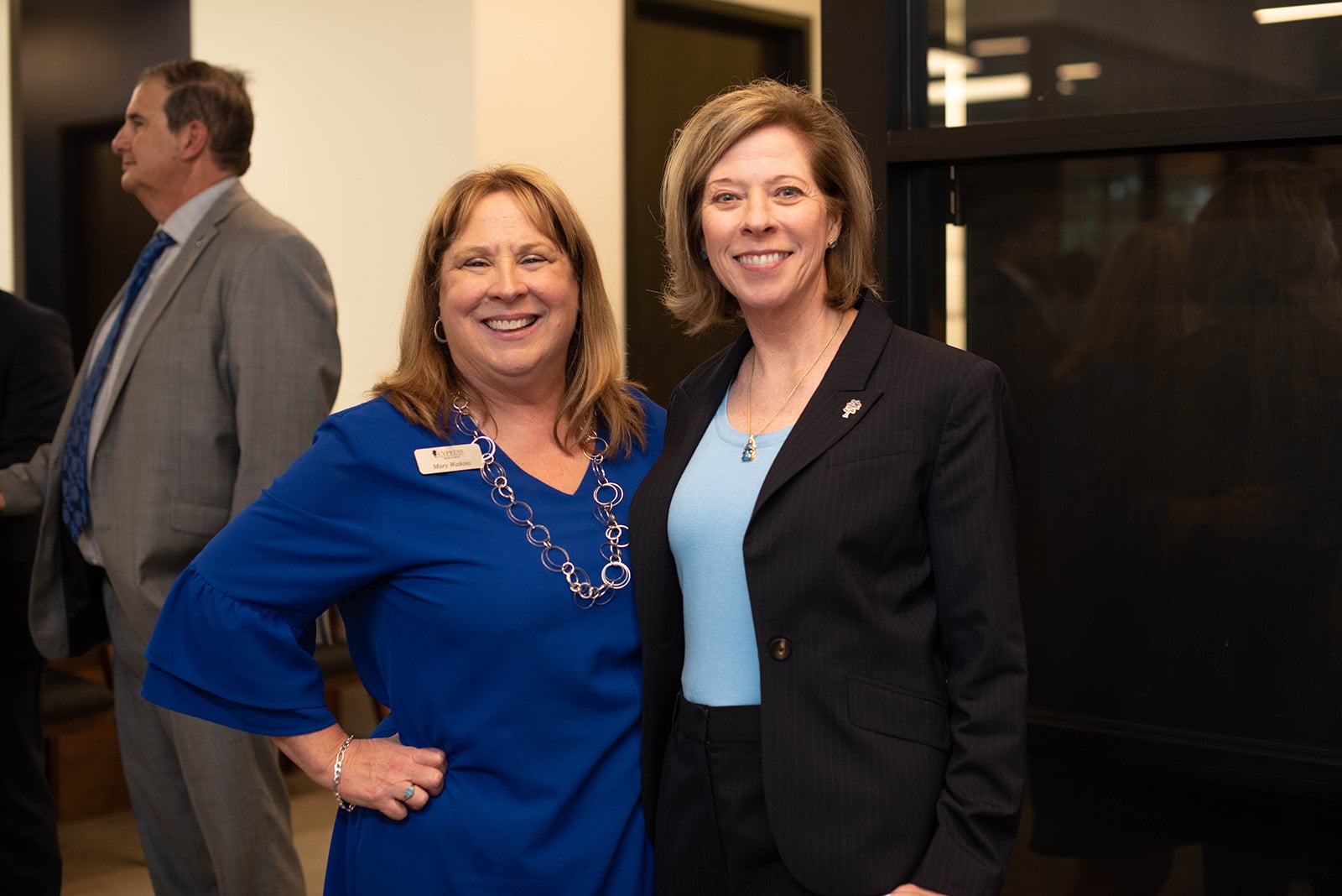 Dos mujeres sonriendo juntas en un evento profesional en interiores